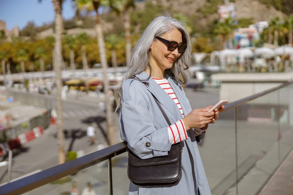 Happy urban woman checking mobile phone outdoors
