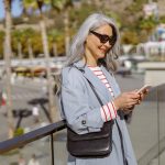 Happy urban woman checking mobile phone outdoors